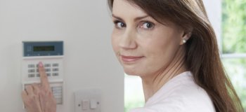 Portrait Of Woman Setting Control Panel On Home Security System